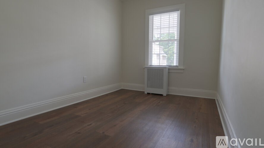 A room with wooden floors and a window with blinds.