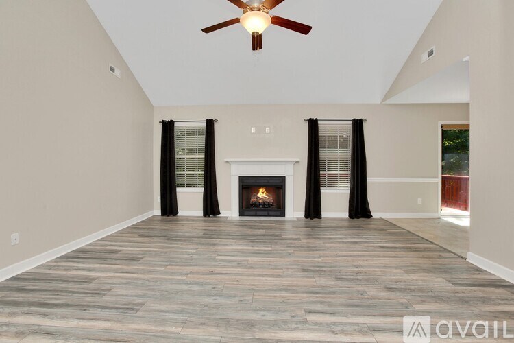 A spacious living room with a fireplace and a ceiling fan.