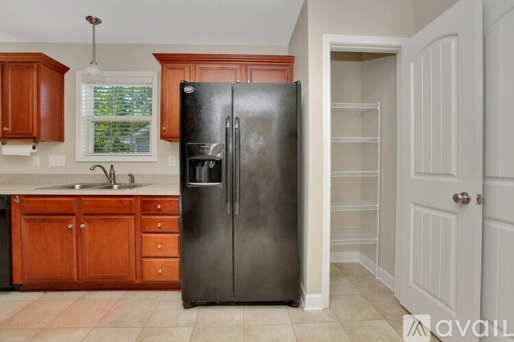 A black refrigerator in a kitchen with wooden cabinets.