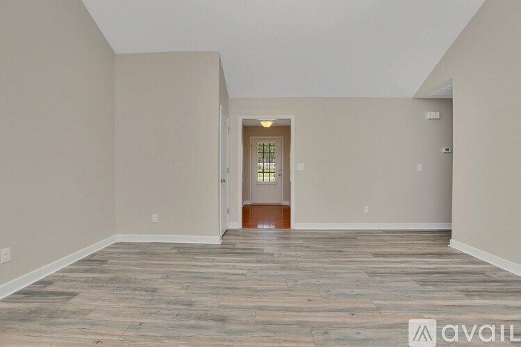 A room with wooden flooring and a doorway leading to another room.