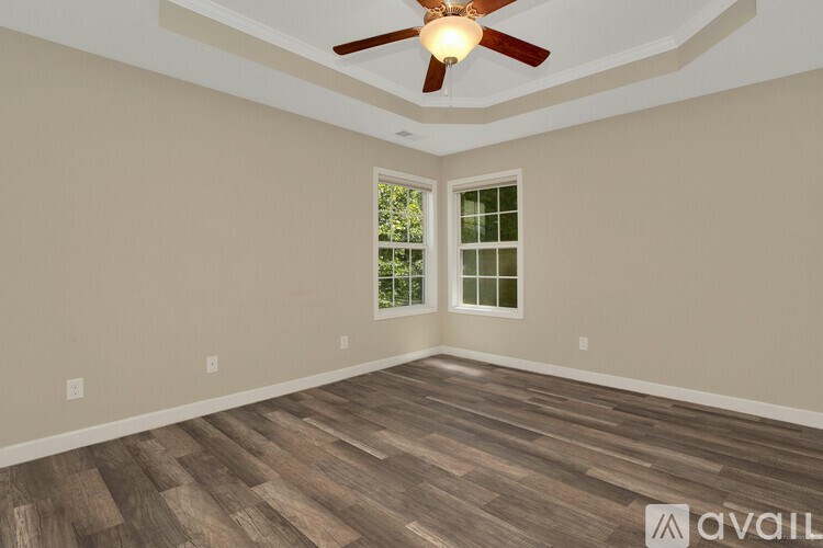 A room with a ceiling fan and wood flooring.