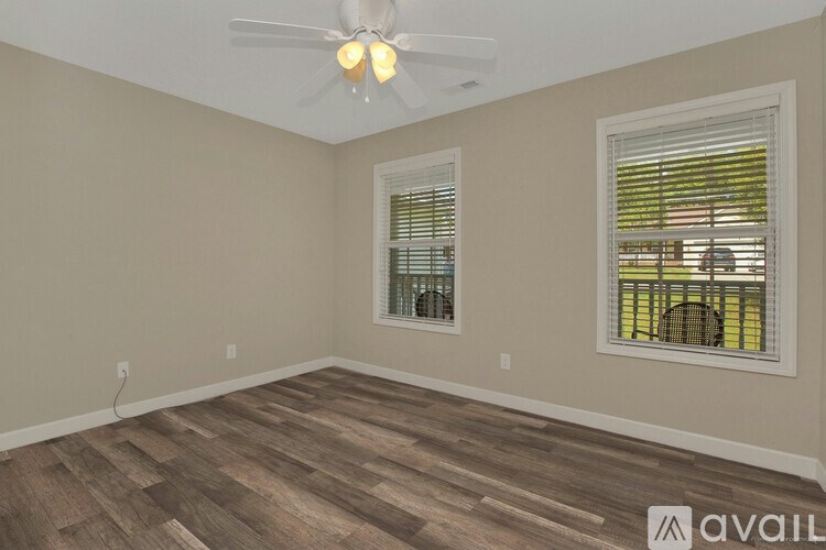 A room with a ceiling fan and two windows with blinds.