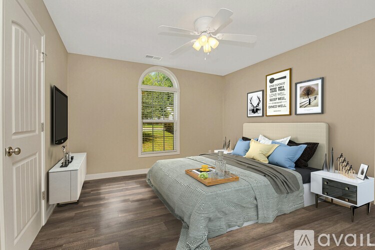 A bedroom with a bed, nightstand, and a window with a view of a tree.