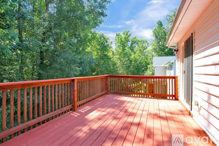 A wooden deck with a railing and trees in the background.