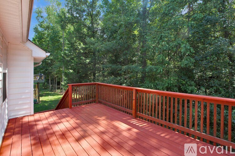 A wooden deck with a railing and trees in the background.
