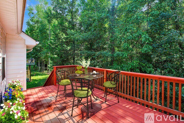 A wooden deck with a table and chairs overlooking a forest.