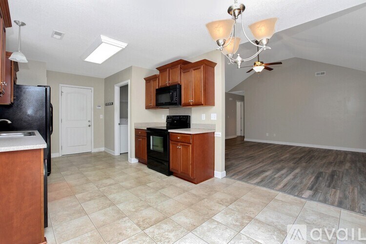 A kitchen with a black fridge and wooden cabinets.