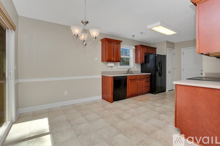 A kitchen with a black refrigerator and wooden cabinets.