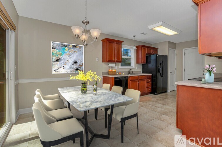 A kitchen with a table and chairs in the foreground and a painting hanging on the wall.