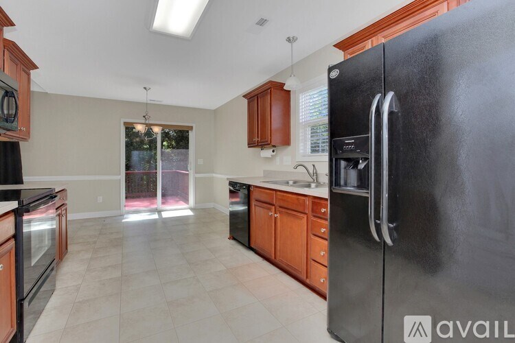 A kitchen with a black fridge and wooden cabinets.
