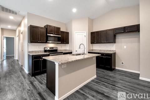 A kitchen with dark brown cabinets and a granite countertop.