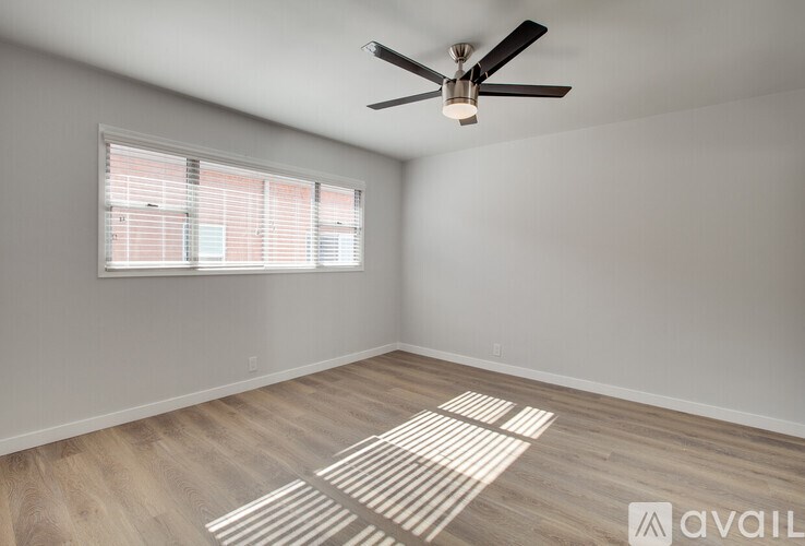 A room with a ceiling fan and a window with blinds.