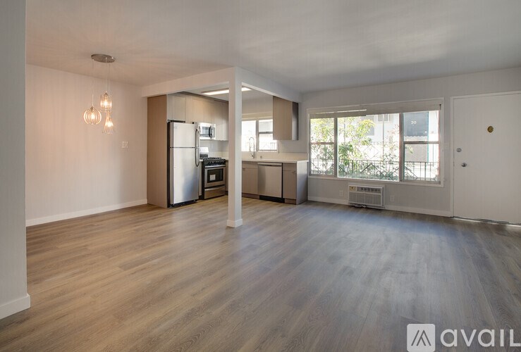 A spacious living room with a kitchen area in the background.
