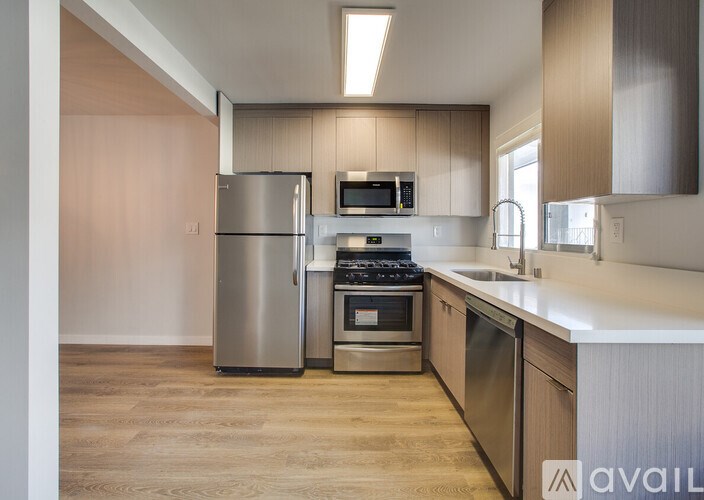 A modern kitchen with stainless steel appliances and wooden flooring.