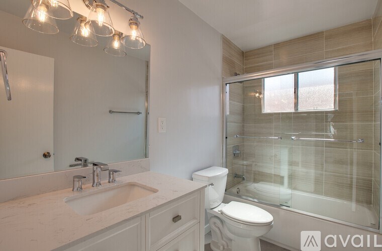 A bathroom with a sink, toilet, and a glass shower stall.