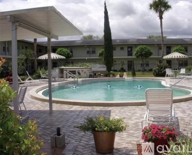 A pool surrounded by chairs and plants.