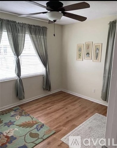 A room with a ceiling fan and a rug on the floor.