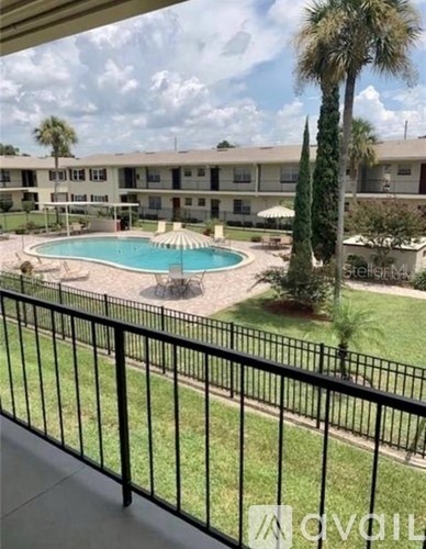A pool and palm tree are visible from a balcony.