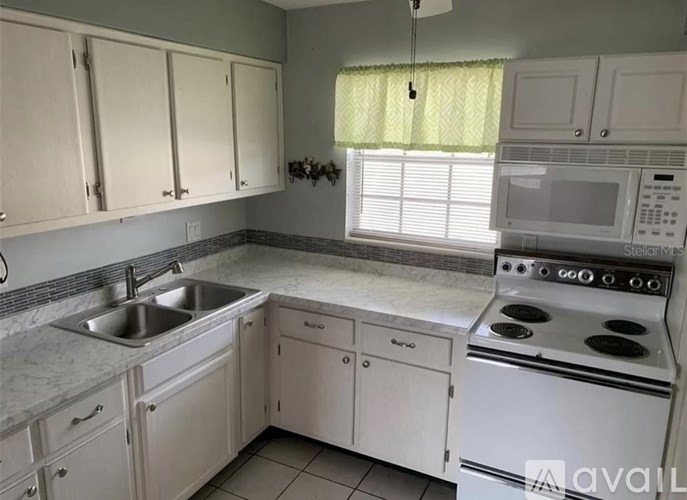 A kitchen with white cabinets and a stove top oven.