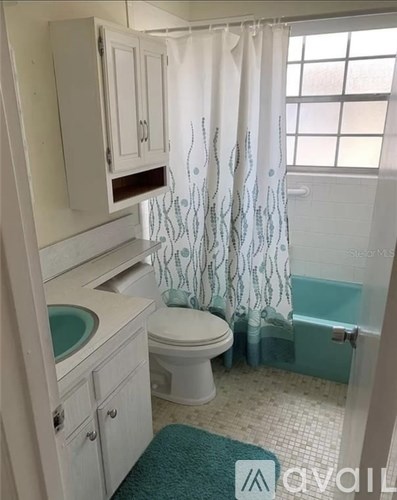 A white bathroom with a toilet, sink, and shower.