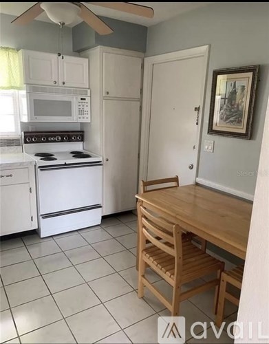 A kitchen with a white oven and microwave, a wooden table, and a painting on the wall.
