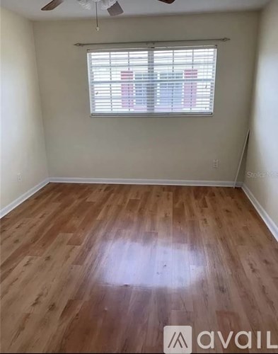 A room with wooden flooring and a window with blinds.