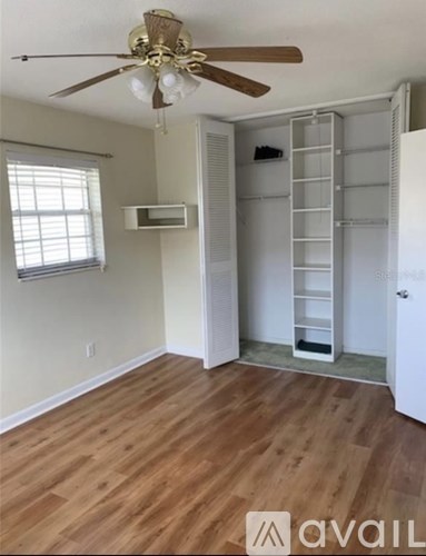A room with a ceiling fan and a built-in shelf unit.