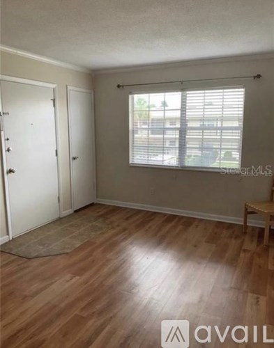 A room with wooden flooring and a window with blinds.