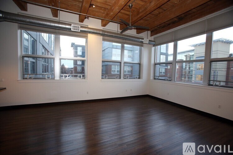 A spacious room with wooden floors and large windows.