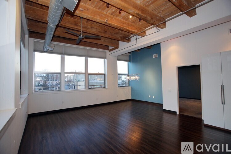 A spacious room with wooden floors and a ceiling fan.