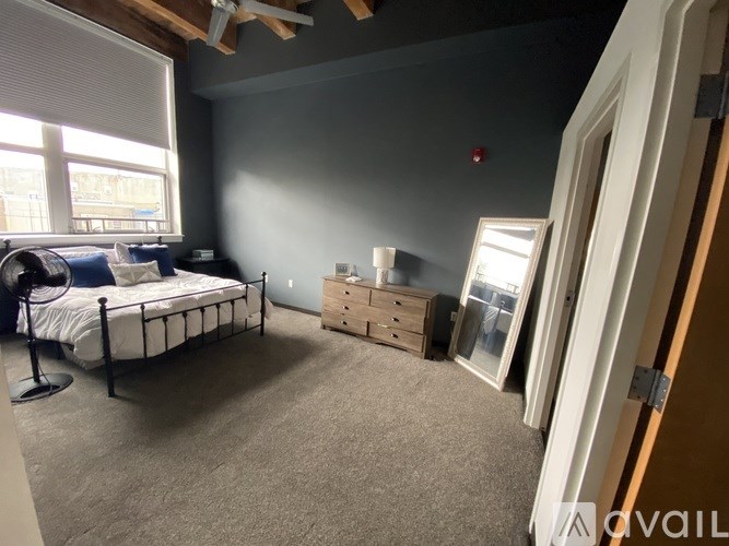 A bedroom with a bed, dresser, and window.