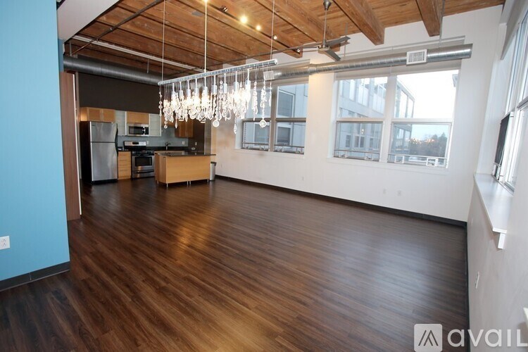 A spacious room with wooden floors and a kitchen area.