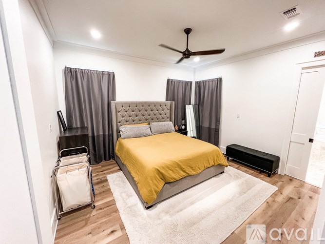 A bedroom with a yellow bedspread and a ceiling fan.