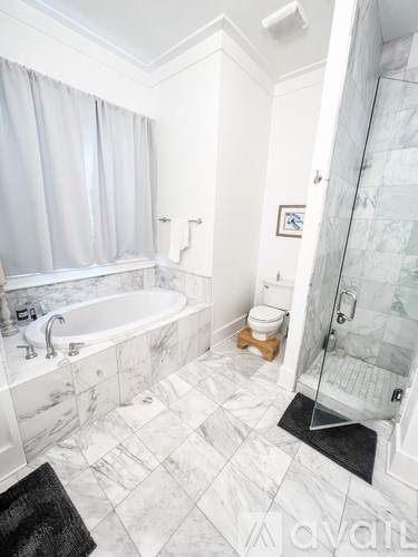 A white bathroom with a marble floor and a glass shower.