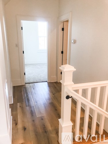 A hallway with a wooden floor and white walls.