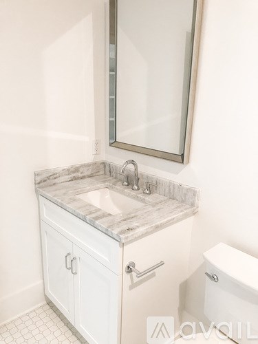 A white bathroom with a marble countertop and a toilet.
