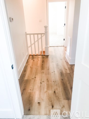 A hallway with wood flooring and white walls.