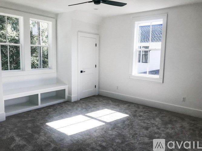 A room with a window seat and a ceiling fan.