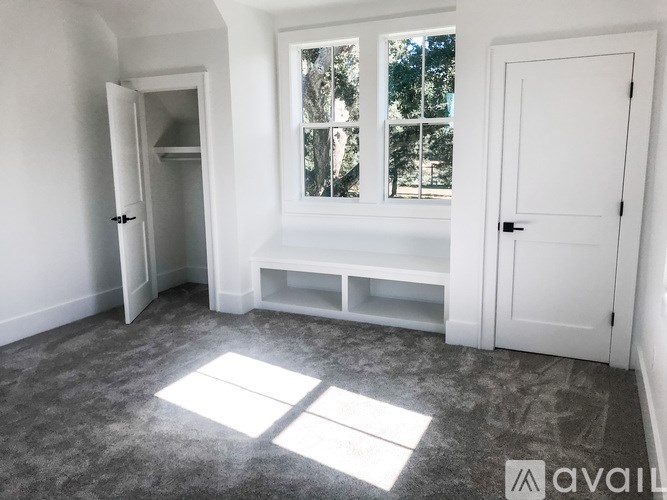 A room with a large window and a bench under it.