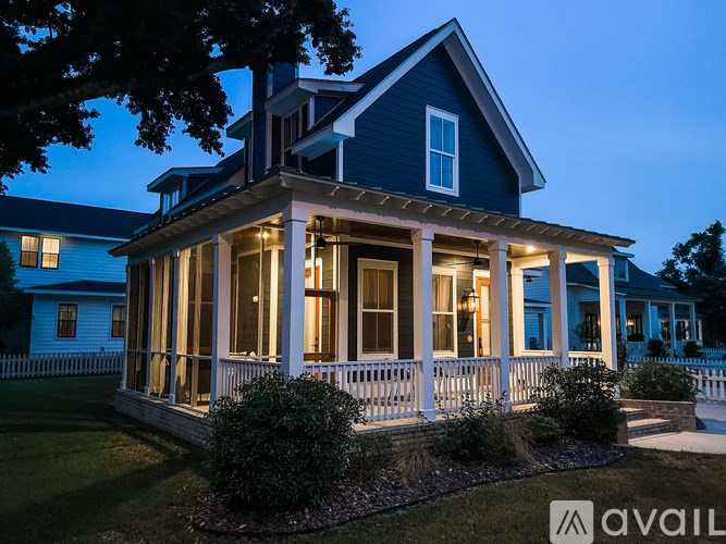 A house with a porch and a tree in front of it.