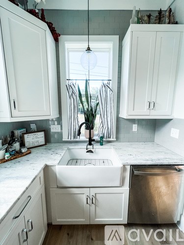 A kitchen with white cabinets and a marble countertop.