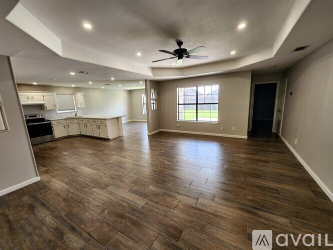 A spacious room with wood flooring and a ceiling fan.
