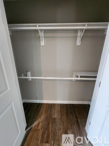 A white closet with a wooden floor and white shelves.