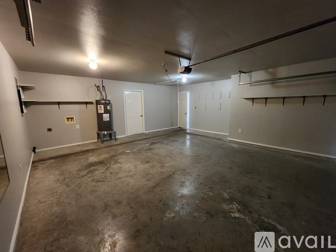 A spacious, empty room with concrete flooring and white walls.