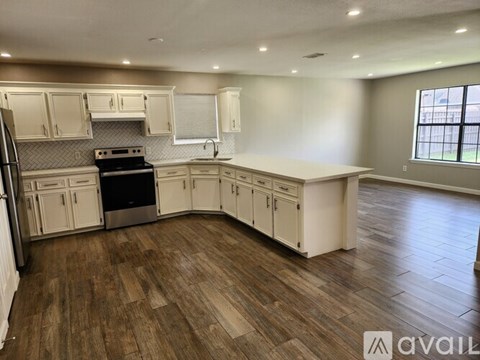 A kitchen with white cabinets and a wooden floor.