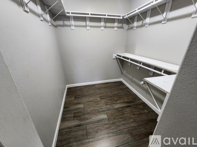 A walk-in closet with white shelving and wood flooring.