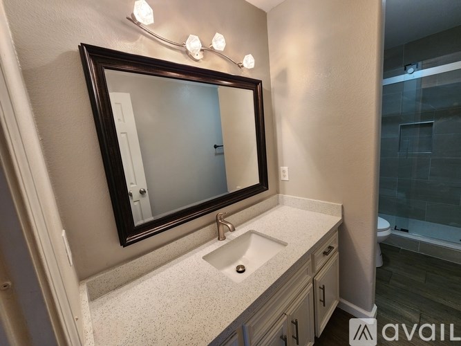 A bathroom with a sink, mirror, and lights.
