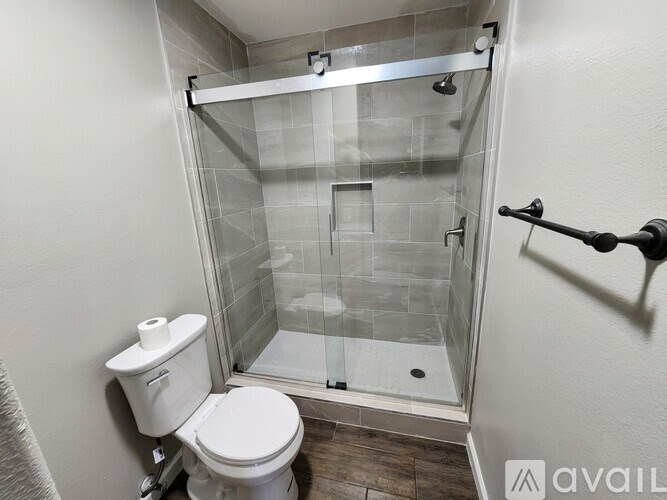A white toilet sits next to a walk-in shower with a glass door.