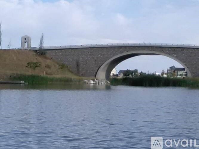 A stone bridge over a body of water with a small tower on the left side.