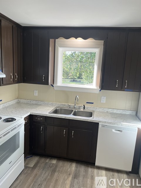 A kitchen with dark brown cabinets and a white dishwasher.
